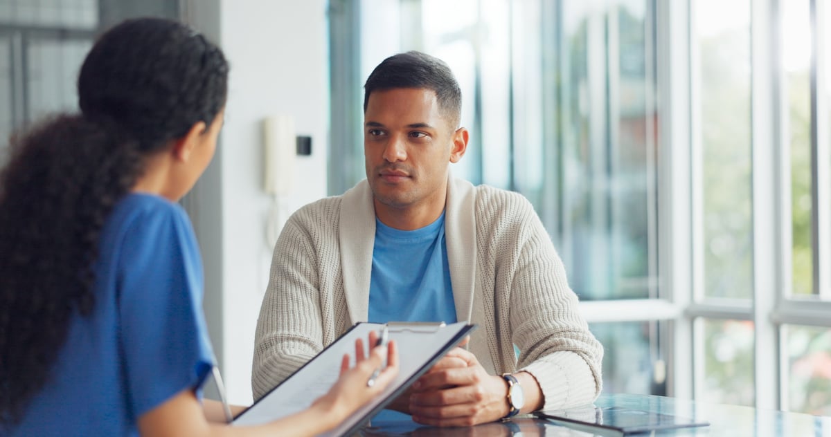Clinician consulting with a patient while reviewing records on a clipboard