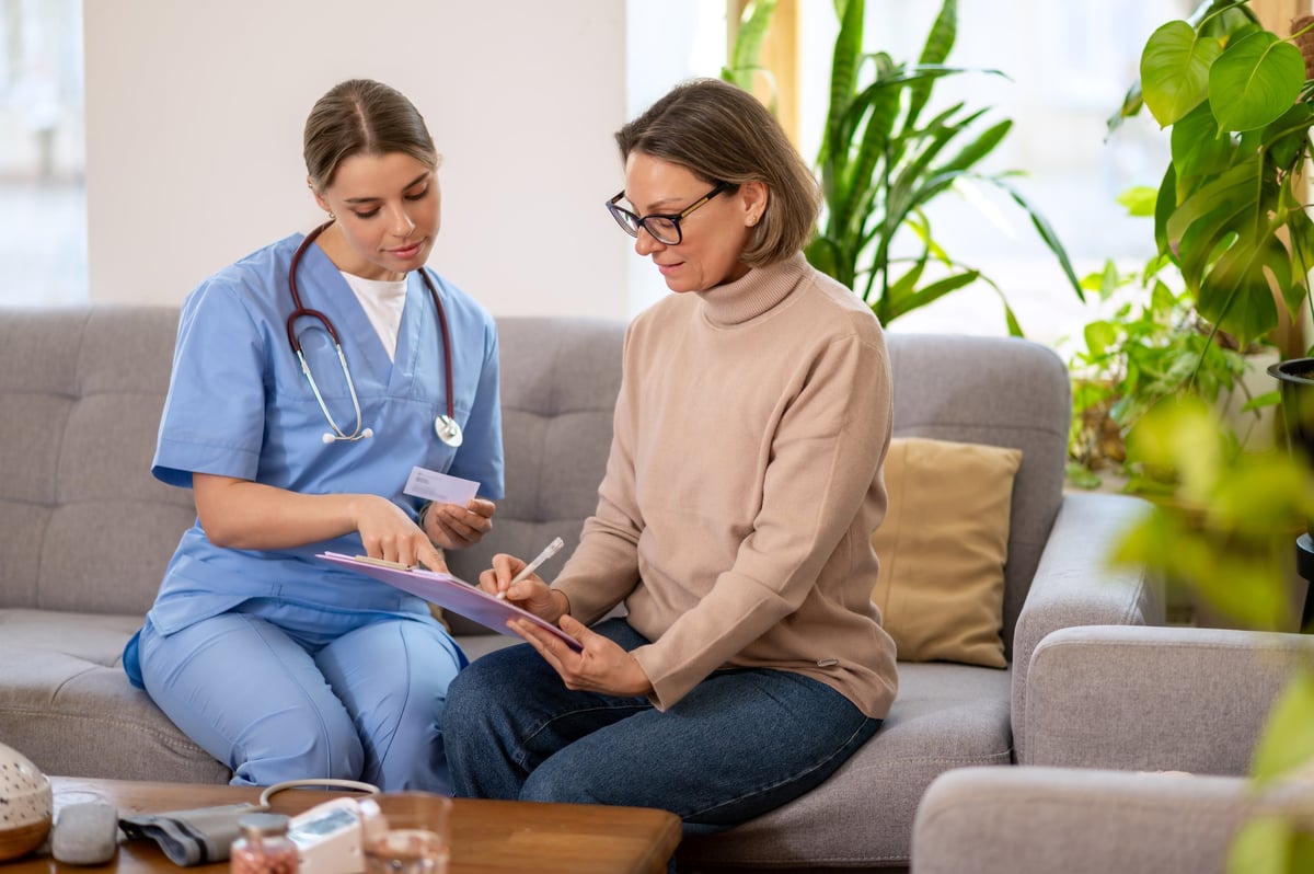 A healthcare professional pointing out where to sign on a clipboard
